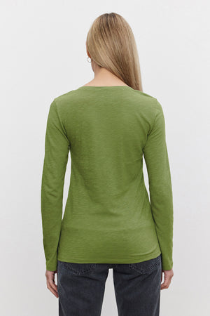 A person with straight, light brown hair wears the Velvet by Graham & Spencer BLAIRE TEE, a long-sleeve green cotton slub shirt, paired with black jeans, shown from the back against a plain light background—ideal for everyday wear.
