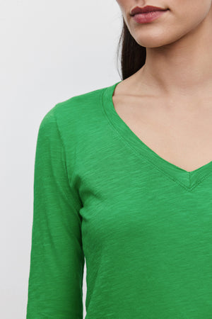 A person wearing a green BLAIRE TEE, long-sleeve shirt made of textured cotton slub by Velvet by Graham & Spencer is shown from the shoulders up, partially cropped to exclude the upper face and eyes.