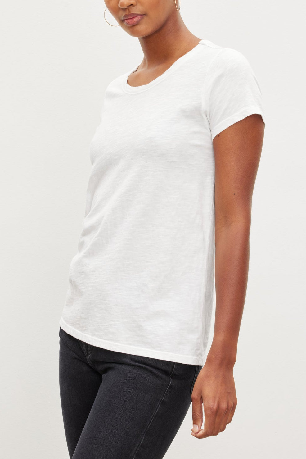 A person wearing a Velvet by Graham & Spencer TILLY TEE in plain white and black pants is standing against a neutral background.