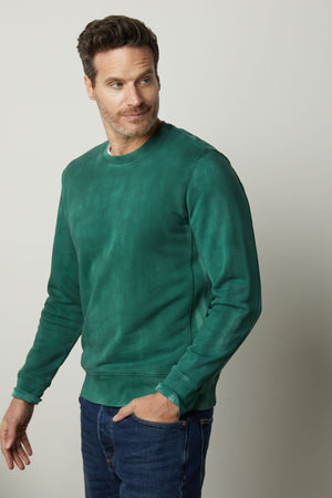 A man wearing a green Velvet by Graham & Spencer MATTS CREW NECK SWEATSHIRT and jeans stays warm in his cozy fleece.