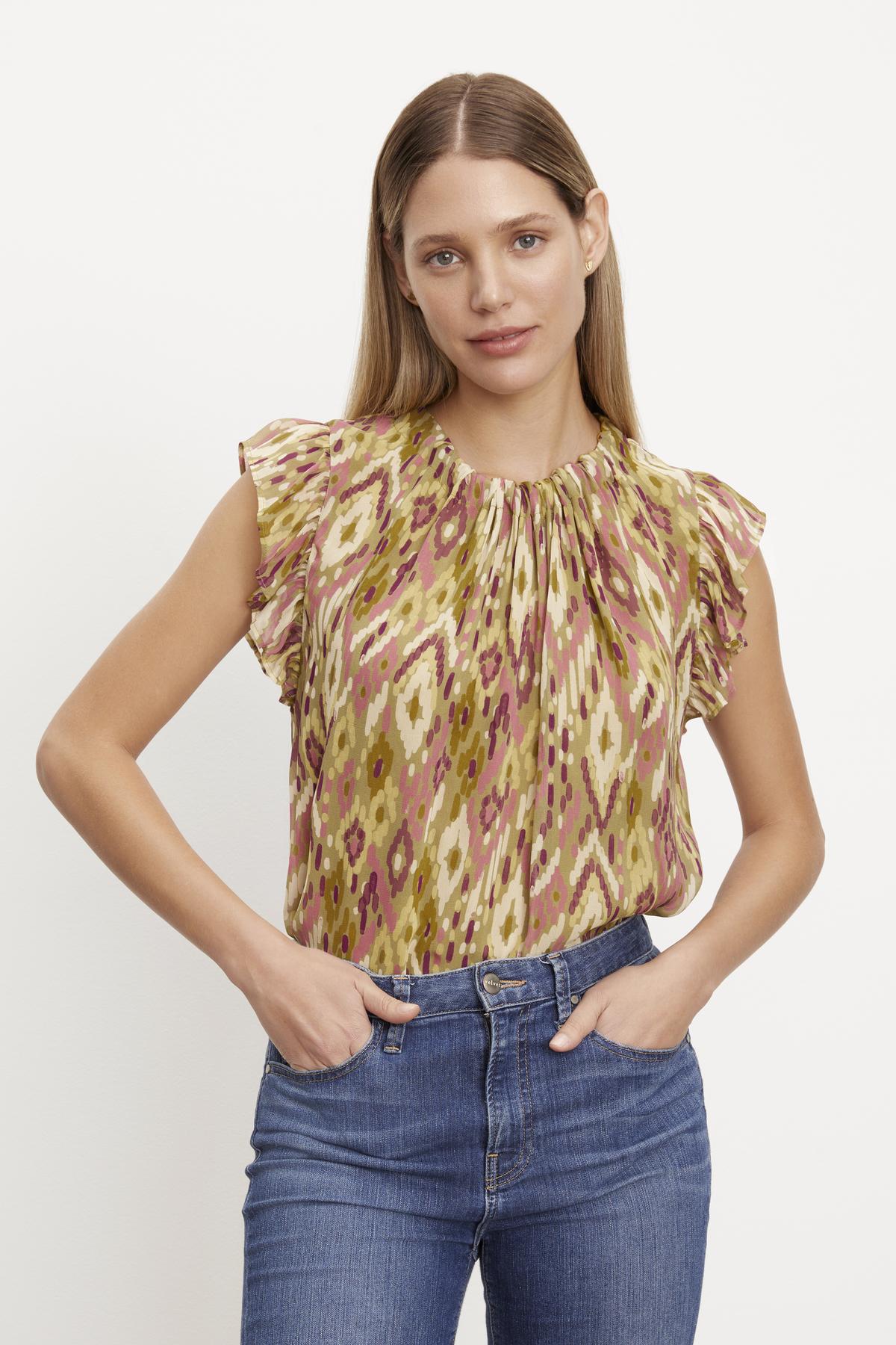 The model is wearing an ADARA PRINTED FLUTTER SLEEVE TOP by Velvet by Graham & Spencer and jeans.