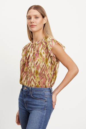 The model is wearing jeans and a Velvet by Graham & Spencer ADARA PRINTED FLUTTER SLEEVE TOP.