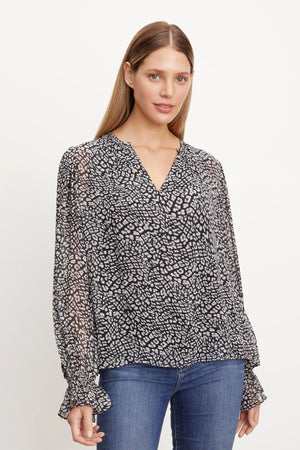 A woman wearing jeans and a Kathy Printed V-Neck Blouse by Velvet by Graham & Spencer exudes femininity.