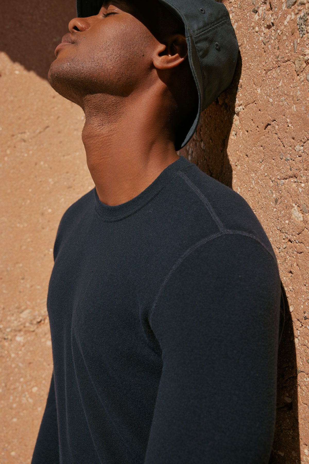 A man wearing a Velvet by Graham & Spencer BECKER COZY JERSEY CREW hat leaning against a wall.