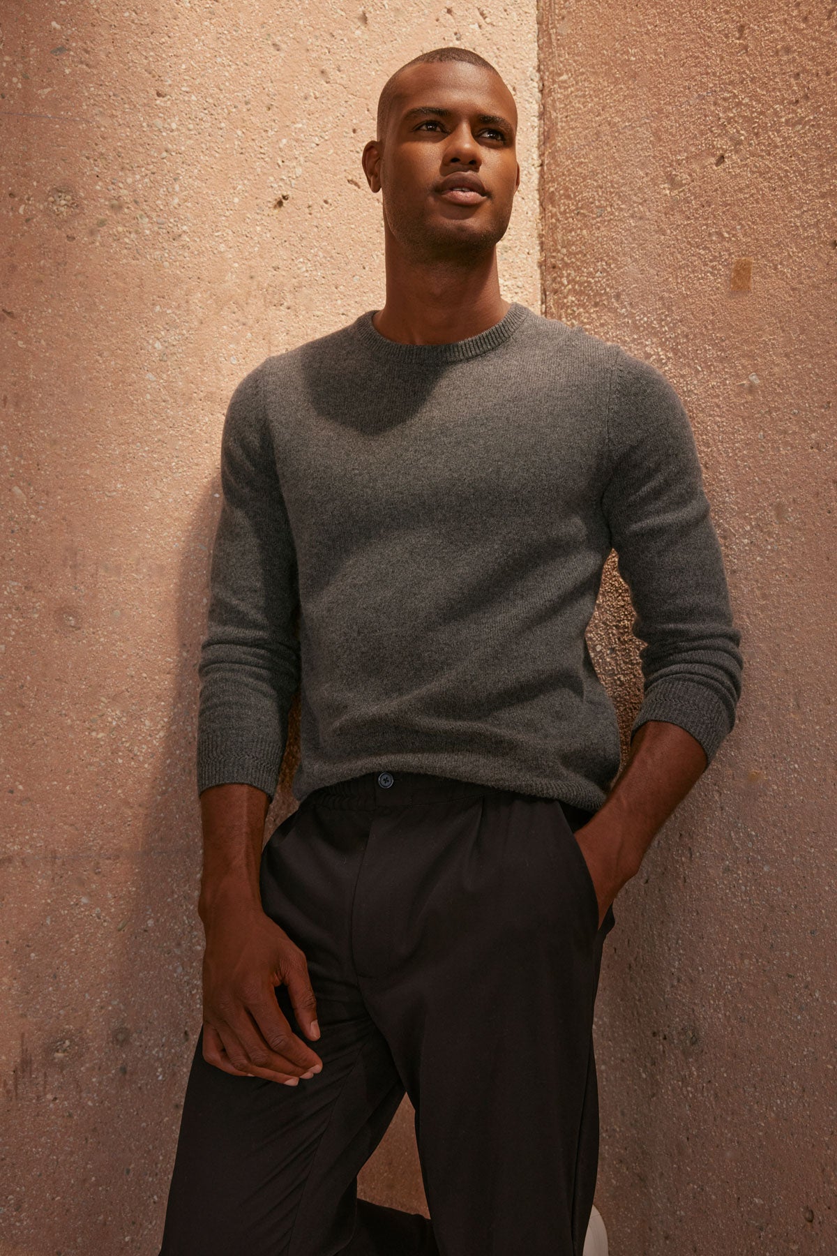 A man in a Velvet by Graham & Spencer DASHELL CREW NECK SWEATER leaning against a wall.-35606055813313
