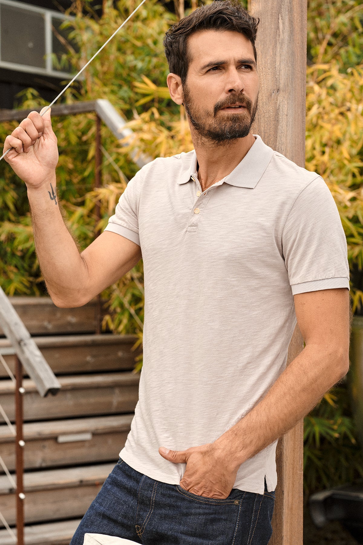 Niko Polo in cobble with dark blue denim, model leaning against wood post outdoors-35206919979201