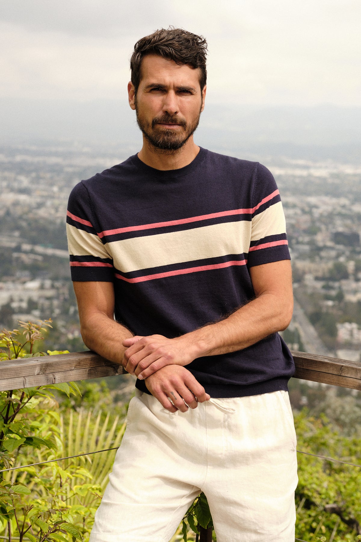 A man wearing a Velvet by Graham & Spencer DEXTER LINEN BLEND STRIPED CREW sweater and white pants.-26468761698497