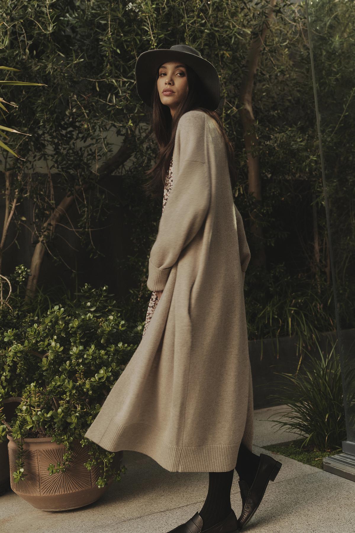 A woman wearing a Velvet by Graham & Spencer LISA WOOL CASHMERE DUSTER CARDIGAN coat and hat.