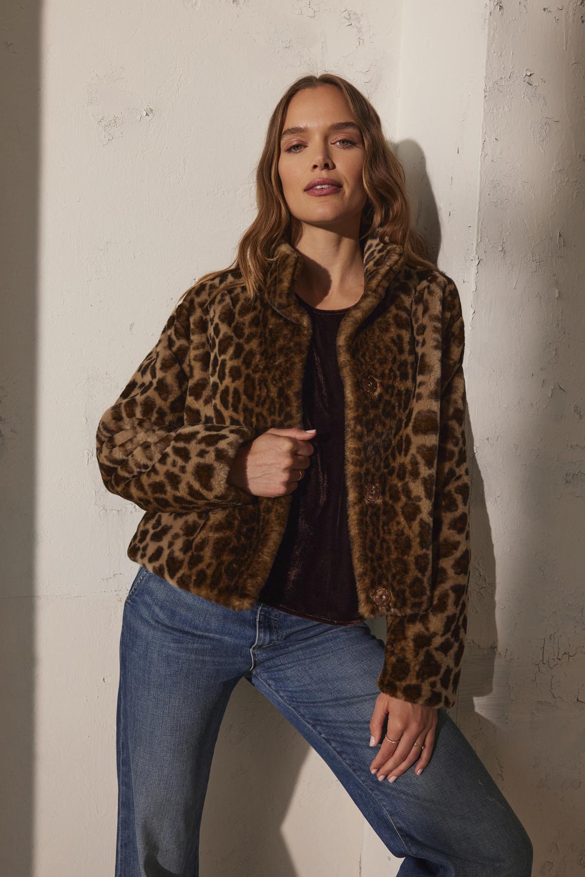 A person in a VALLI FAUX FUR JACKET by Velvet by Graham & Spencer and jeans poses against a textured wall.-38246727942337
