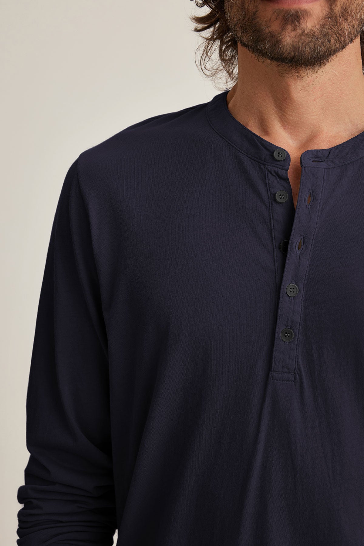 A person in a navy blue Velvet by Graham & Spencer ALVARO HENLEY, a Pima jersey long-sleeve shirt with four buttons, is seen from the shoulders up facing forward against a neutral background. Perfect for layering, this classic piece offers both comfort and style.-39025854972097