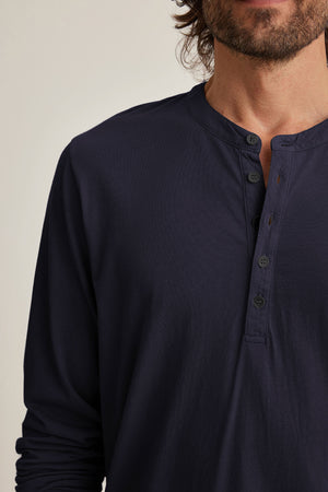 A person in a navy blue Velvet by Graham & Spencer ALVARO HENLEY, a Pima jersey long-sleeve shirt with four buttons, is seen from the shoulders up facing forward against a neutral background. Perfect for layering, this classic piece offers both comfort and style.