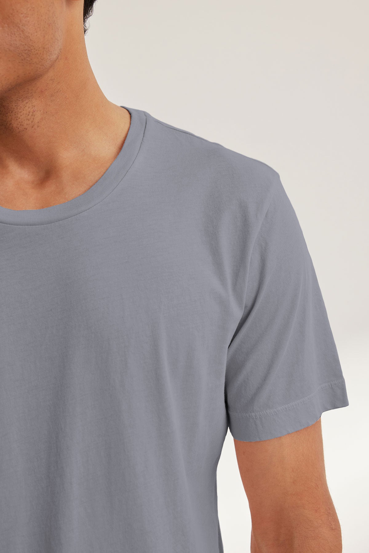 A person is shown from the shoulders up, with only the lower face visible, wearing the Velvet by Graham & Spencer HOWARD TEE—a light gray, short-sleeve t-shirt crafted from lightweight Pima jersey.-40117592457409
