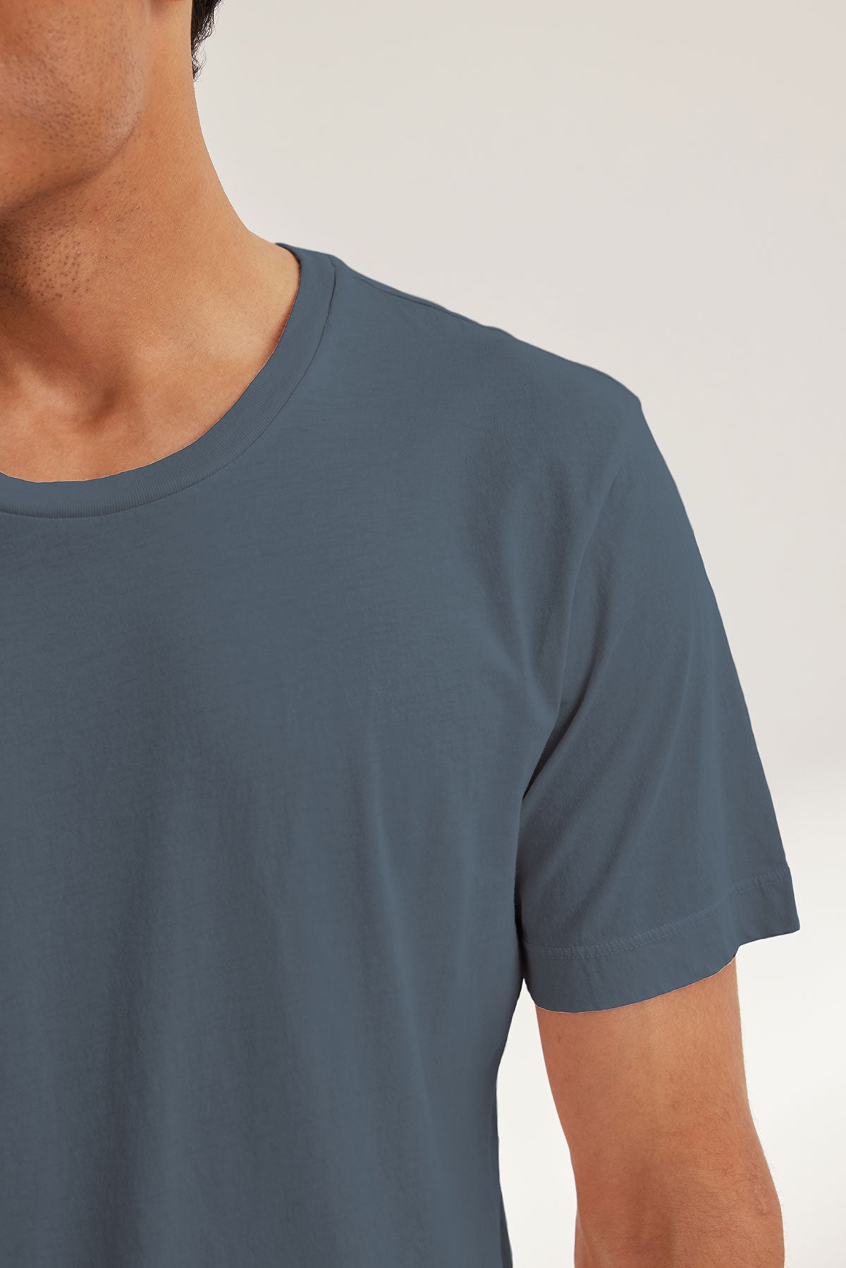A person is shown from the upper torso up, wearing the Velvet by Graham & Spencer HOWARD TEE in plain blue-gray Pima jersey with short sleeves, against a neutral background.-40117588263105