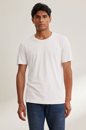 A man faces forward against a neutral background, wearing the Velvet by Graham & Spencer HOWARD TEE in soft Pima jersey and blue jeans.