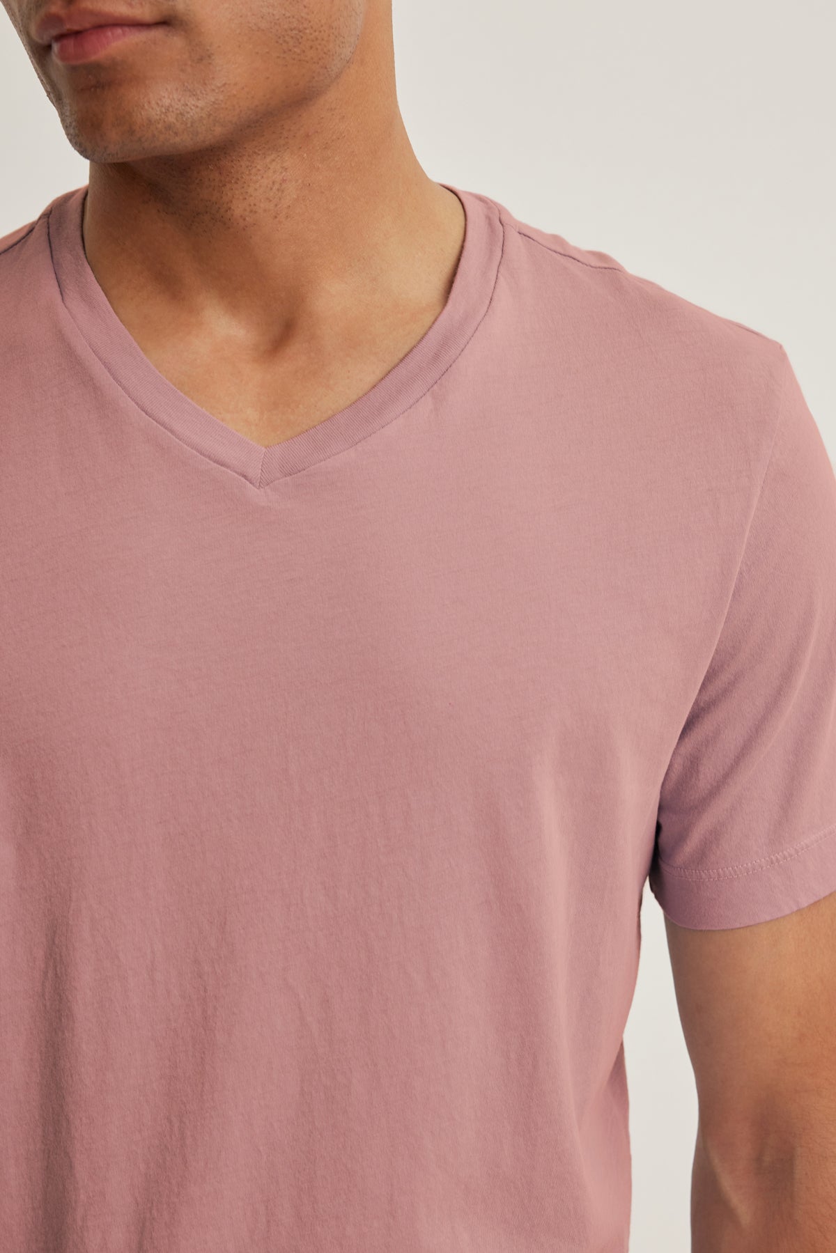 A person wears the SAMSEN TEE by Velvet by Graham & Spencer—a light mauve, V-neck Pima jersey top—shown from shoulders to above the waist, perfect for everyday wear.-40054354280641