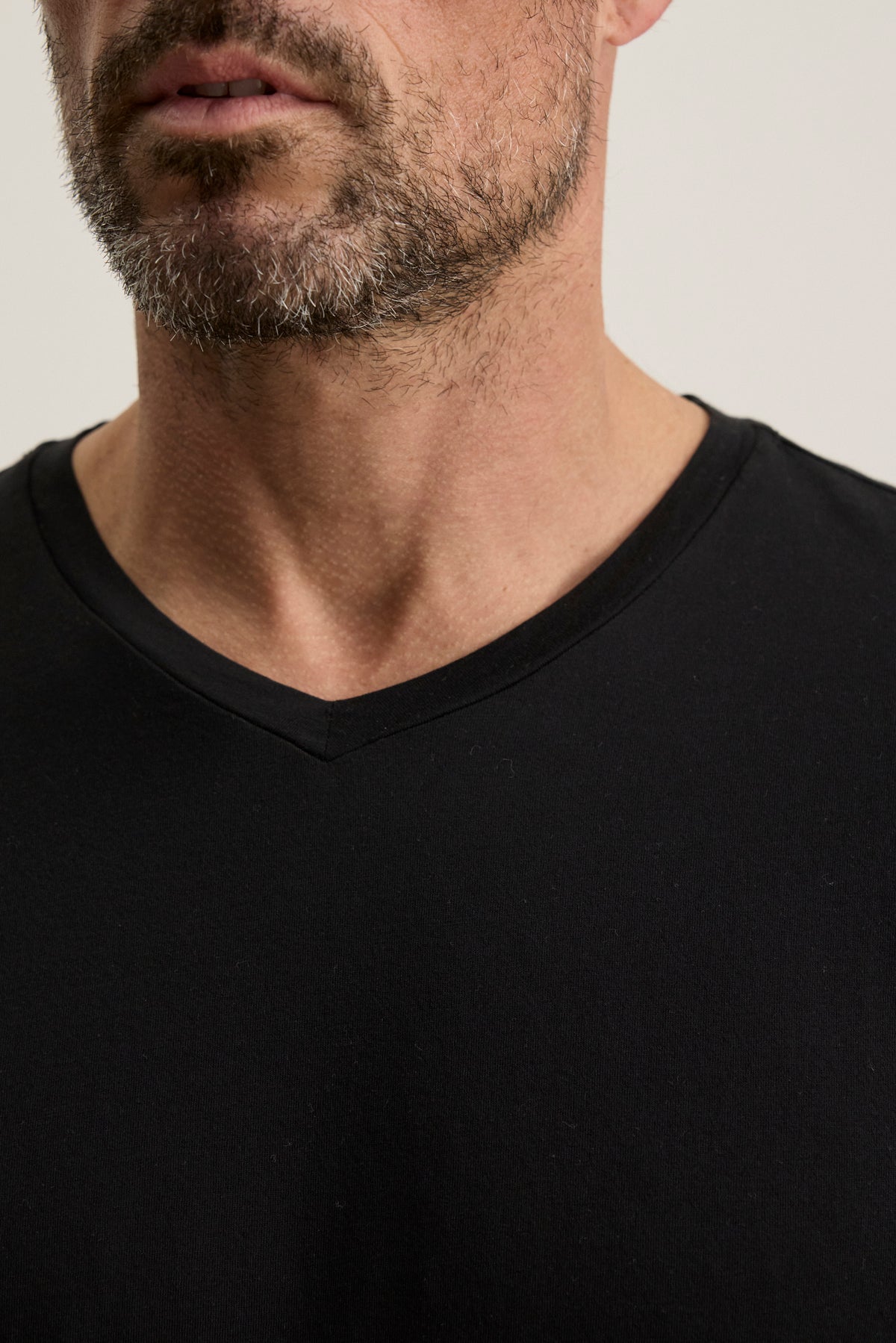 A close-up of a man wearing the SAMSEN TEE by Velvet by Graham & Spencer, showcasing its rich Pima jersey fabric and highlighting his beard and neck.