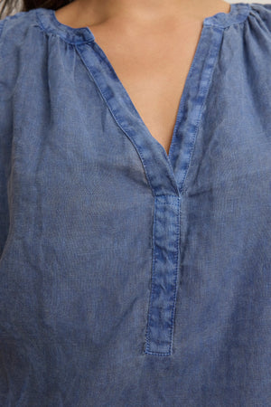 Close-up of a person wearing the TACY LINEN TANK TOP by Velvet by Graham & Spencer, a sleeveless woven linen top with a v-neckline and gathered shoulder detail.