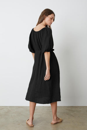 The back view of a woman wearing the Velvet by Graham & Spencer ELLY LINEN MIDI DRESS with a detachable belt.
