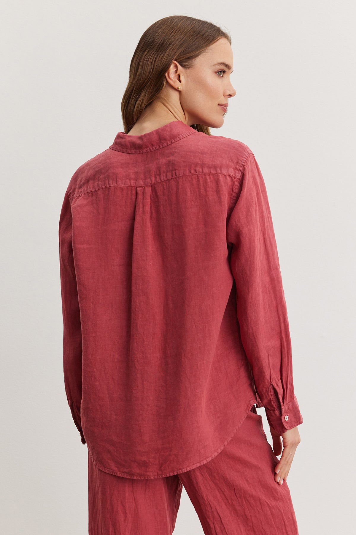 Woman wearing a red WILLOW LINEN BUTTON-UP SHIRT by Velvet by Graham & Spencer, viewed from behind, with focus on the shirt's design details like the yoke and gathered fabric.-36909598343361