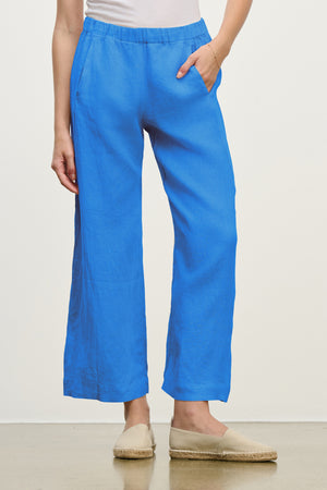 A person wearing Velvet by Graham & Spencer's LOLA LINEN PANT in bright blue and beige espadrilles stands against a plain light background.