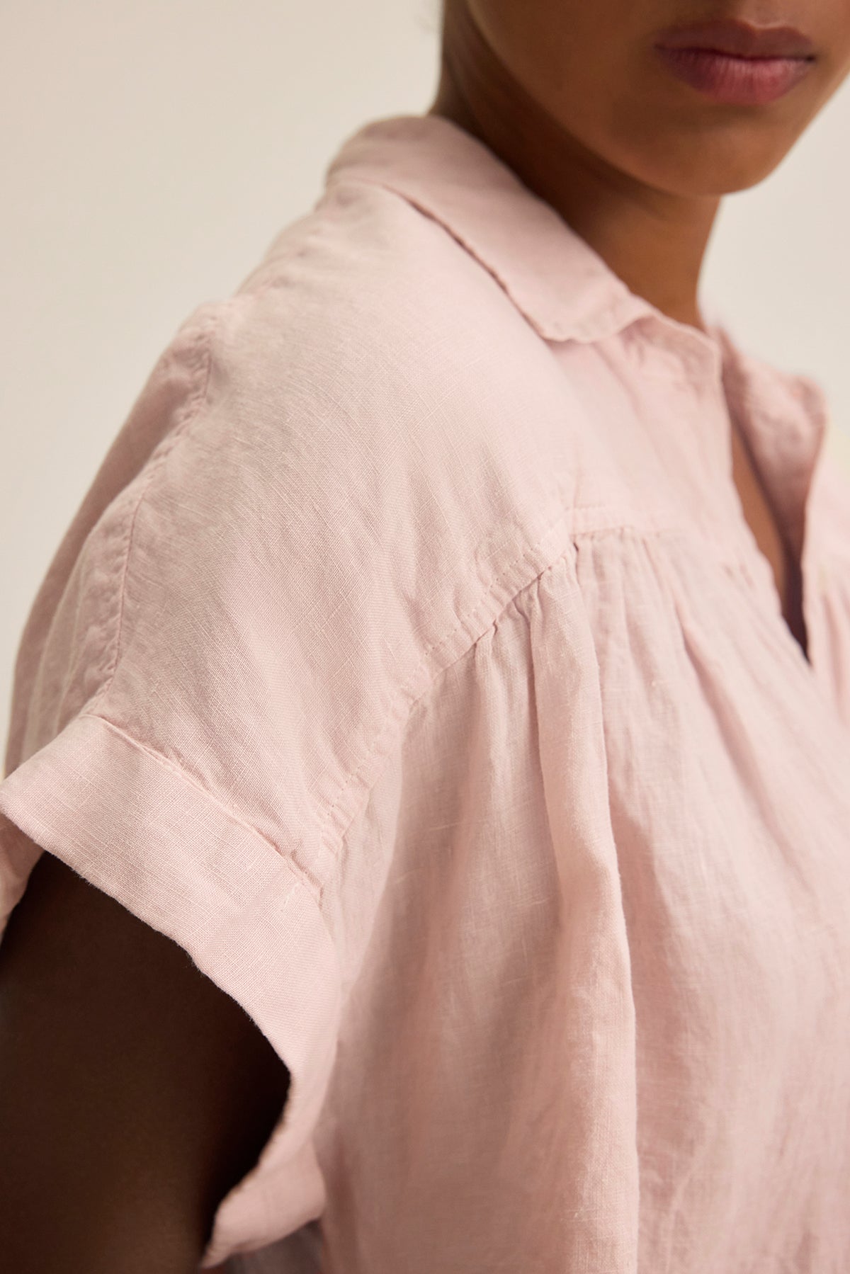 The ARIA LINEN TOP by Velvet by Graham & Spencer is shown in light pink, featuring short sleeves and a button front, displayed from shoulder to chin against a neutral backdrop.