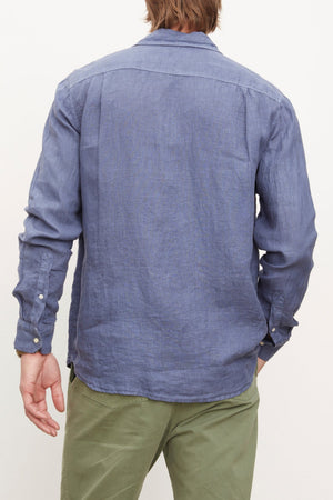 The back of a stylish man wearing a Velvet by Graham & Spencer BENTON LINEN BUTTON-UP SHIRT and green pants.