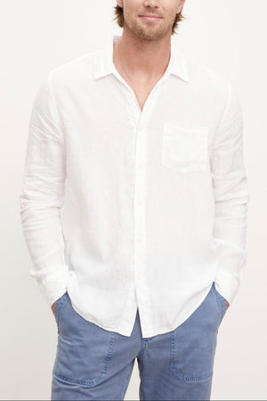 A stylish man wearing a Velvet by Graham & Spencer BENTON LINEN BUTTON-UP SHIRT and blue pants.