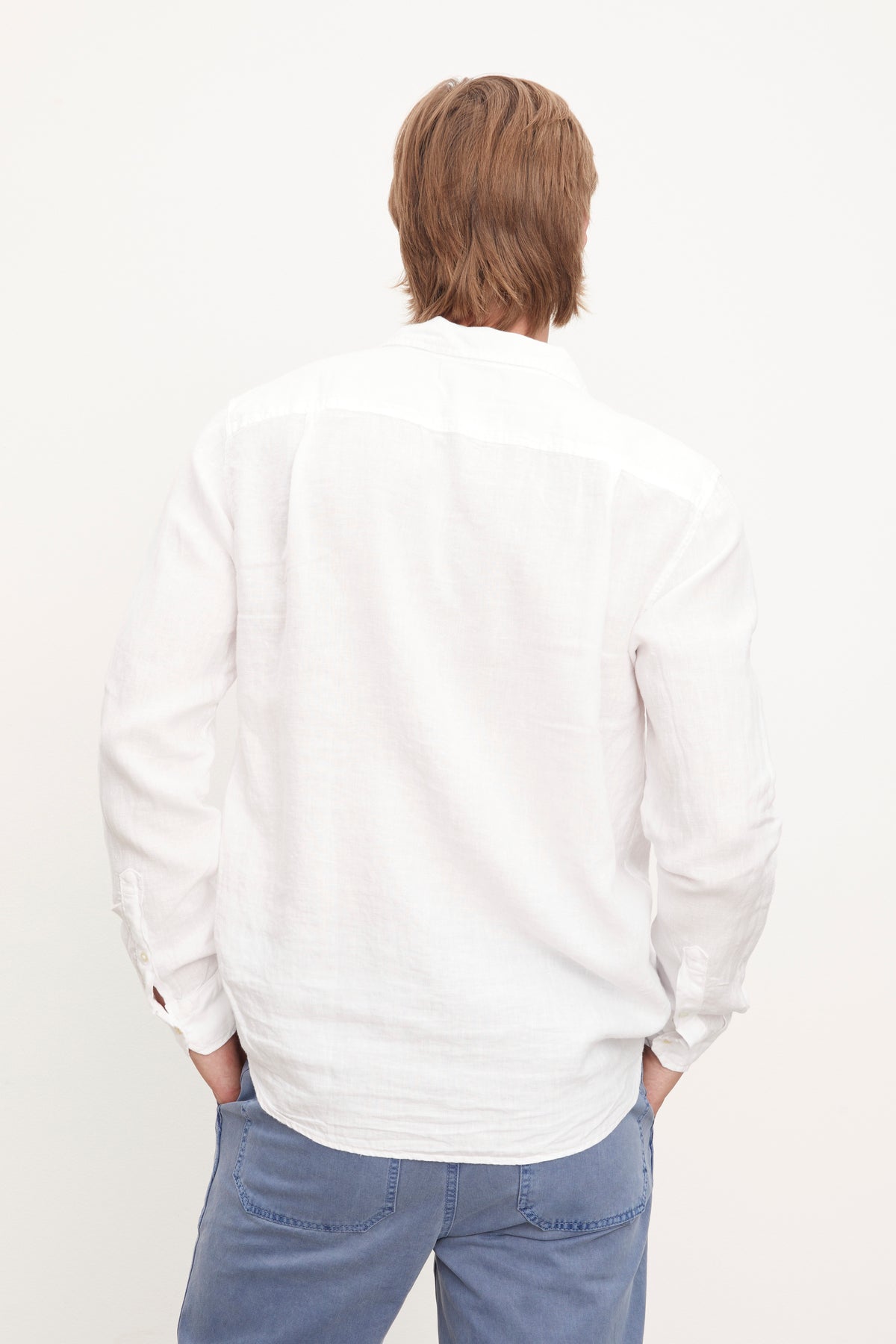 The stylish man in a Velvet by Graham & Spencer Benton Linen Button-Up Shirt, paired with blue pants.-36009360195777