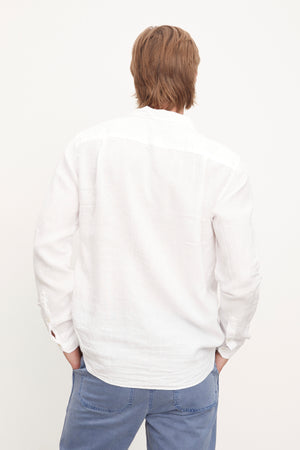 The stylish man in a Velvet by Graham & Spencer Benton Linen Button-Up Shirt, paired with blue pants.