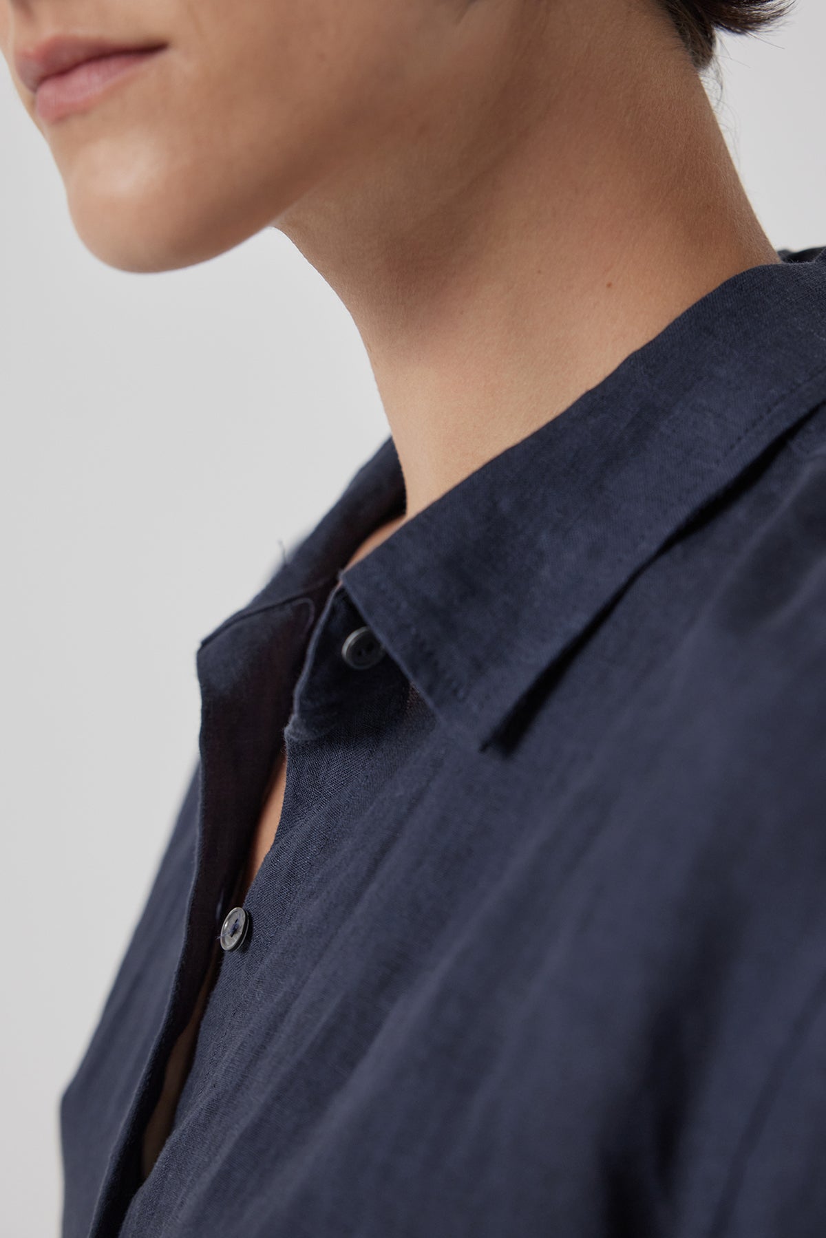   Close-up of a person wearing a Velvet by Jenny Graham Claremont Linen Shirt focusing on the collar and a partial view of their lower face. 