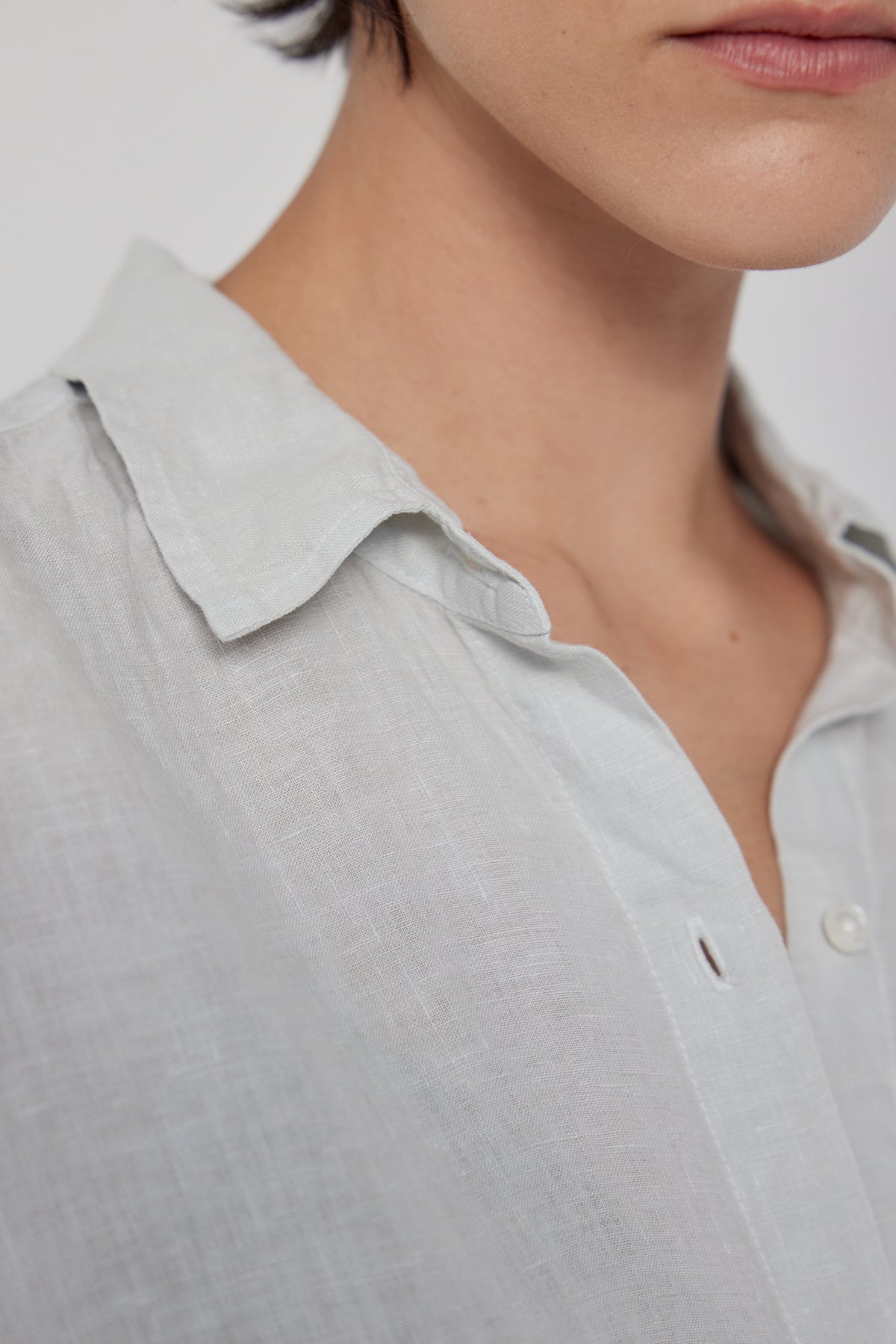 Close-up of a person wearing a Velvet by Jenny Graham Claremont Linen Shirt, focusing on the collar and top button, with part of their lower face visible.-36168678310081