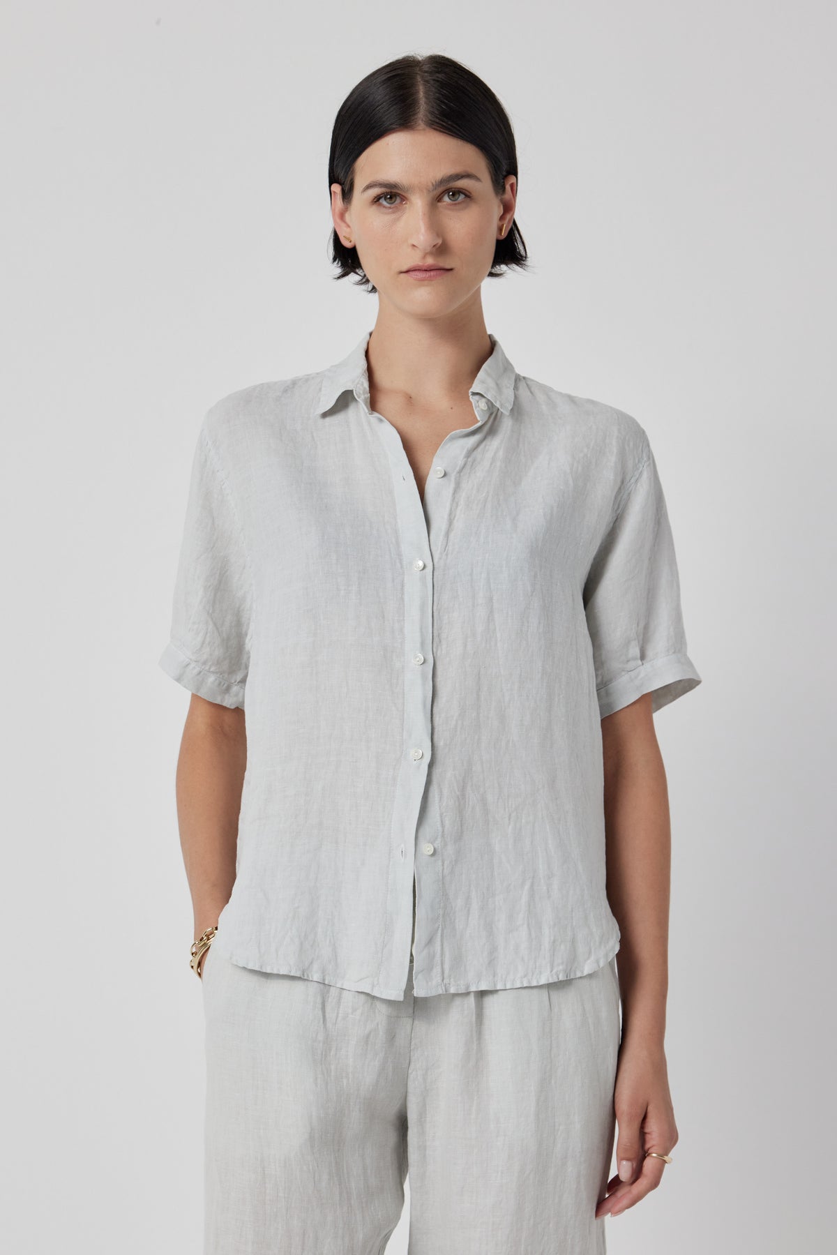 Woman in a casual CLAREMONT LINEN SHIRT by Velvet by Jenny Graham and trousers, standing against a plain white background.-36168678277313