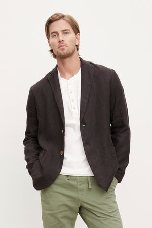 A man wearing a relaxed Velvet by Graham & Spencer Joshua Linen Blazer and green pants.