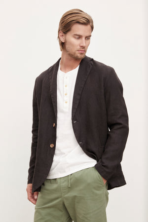 A man wearing a Velvet by Graham & Spencer JOSHUA LINEN BLAZER and relaxed green pants.