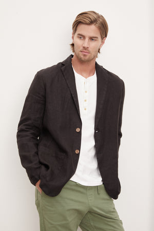 A man wearing a black Velvet by Graham & Spencer JOSHUA LINEN BLAZER and green pants.