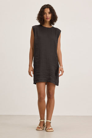 A person in the LARA LINEN DRESS by Velvet by Graham & Spencer and sandals stands against a plain white background.