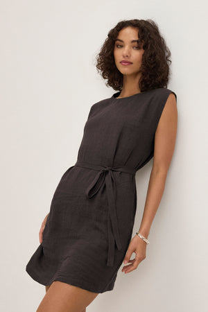 A woman models the LARA LINEN DRESS by Velvet by Graham & Spencer—a sleeveless, lightweight linen dress with a detachable waist belt—against a plain light background.