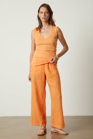 a woman wearing a Velvet by Graham & Spencer ESTINA GAUZY WHISPER FITTED TANK TOP and wide leg pants.