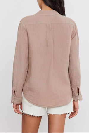 Woman from behind, wearing a NATALIA LINEN BUTTON-UP SHIRT by Velvet by Graham & Spencer and white shorts, standing against a plain background.