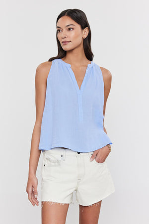 A woman in a Velvet by Graham & Spencer TACY LINEN TANK TOP and white frayed shorts standing against a white background.