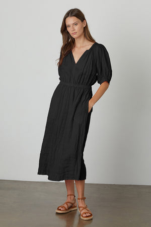 A model wearing a Velvet by Graham & Spencer WHITNEY LINEN CUT OUT DRESS and sandals.