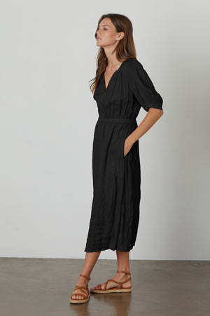 A woman wearing a Velvet by Graham & Spencer WHITNEY LINEN CUT OUT DRESS and sandals.