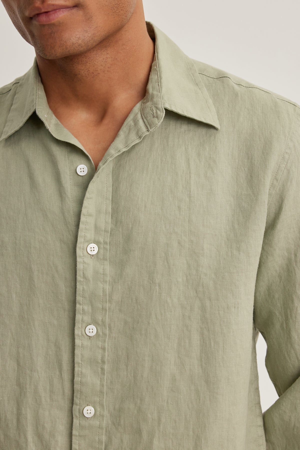 A person wearing the Velvet by Graham & Spencer CARUSO LINEN BUTTON-UP SHIRT in light green, collar open, shown chest up.-39152342859969