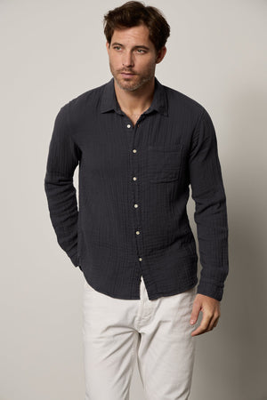 a man wearing a Velvet by Graham & Spencer ELTON BUTTON-UP SHIRT and white pants.