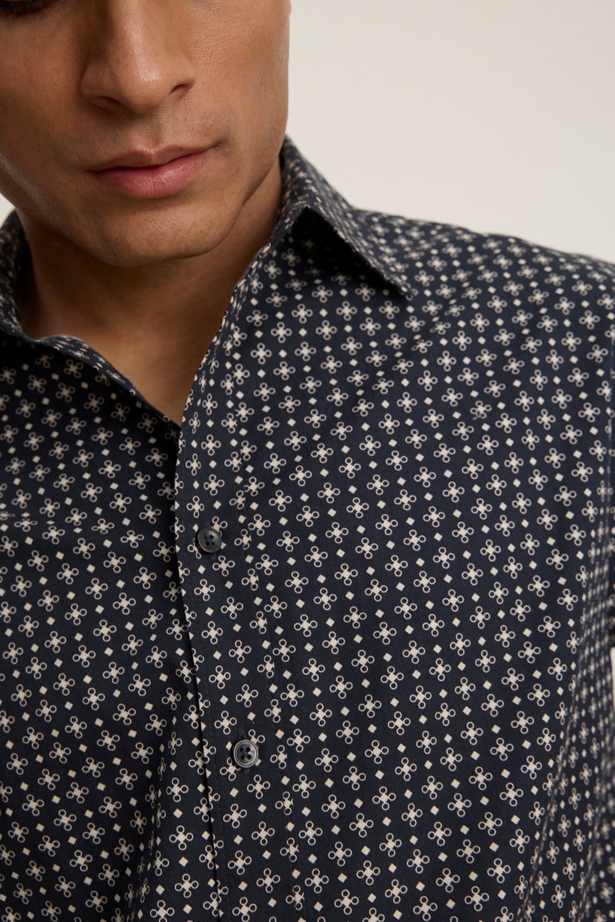 Wearing the LAWRENCE BUTTON-UP SHIRT by Velvet by Graham & Spencer, featuring a classic fit and light-colored geometric pattern; only the lower face and torso are shown, emphasizing its tailored style.
