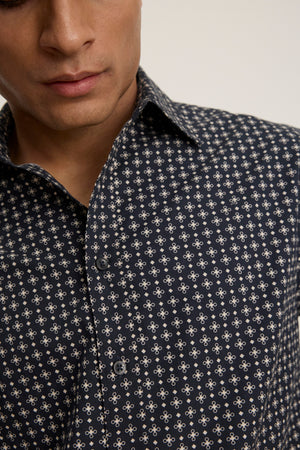 Wearing the LAWRENCE BUTTON-UP SHIRT by Velvet by Graham & Spencer, featuring a classic fit and light-colored geometric pattern; only the lower face and torso are shown, emphasizing its tailored style.