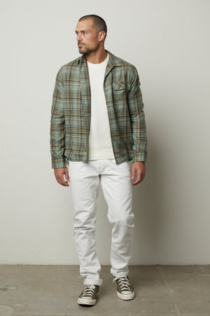 A man wearing white jeans and a Velvet by Graham & Spencer TIMOTHY PLAID BUTTON-UP SHIRT.