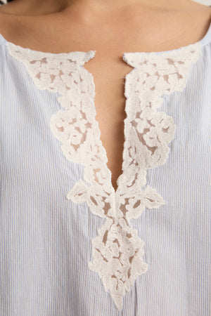Close-up of the PENELOPE BLOUSE by Velvet by Graham & Spencer, a light blue and white striped boatneck top with a V-shaped neckline and delicate white lace detailing.