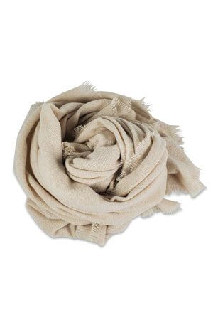 The COZY SOLID SCARF by Velvet by Graham & Spencer is a light beige, textured jumbo scarf with frayed edges, loosely rolled in a circle on a white background—an essential for cozy winter style.