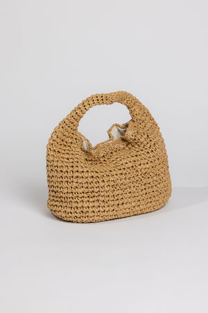 Woven paper straw slouch bag with a single handle, featuring a natural beige color and a soft inner lining, set against a light gray background by Velvet by Graham & Spencer.